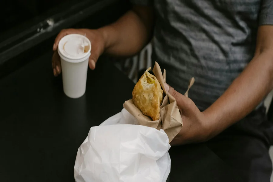 A person holding a cup of coffee and a food